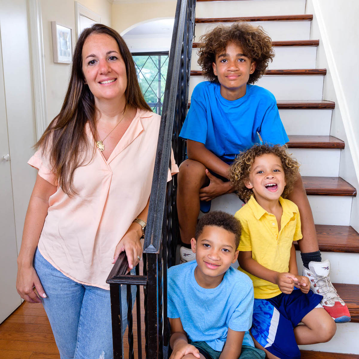 Mom stands outside with two sons and their bike